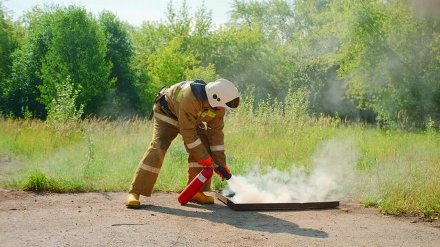 Firefighter using fire extinguisher on flames from the burning underground construction. Clip. Red flame rising up from an opened hatch.