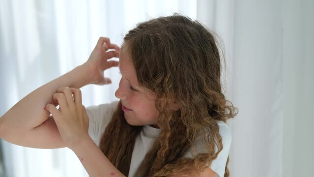 The child scratches his head with a rash. Itching from chickenpox in a girl.