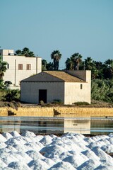 Vertical shot of a white building on the shore in the salt evaporation pond. Marsala, Sicily, Italy.