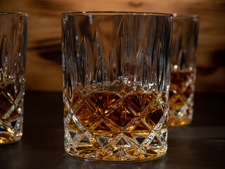 Whiskey, bourbon or cognac on a black and wooden background.