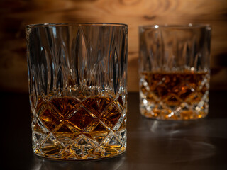Whiskey, bourbon or cognac on a black and wooden background.
