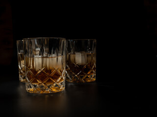 Whiskey, bourbon or cognac with ice cubes on a black background.