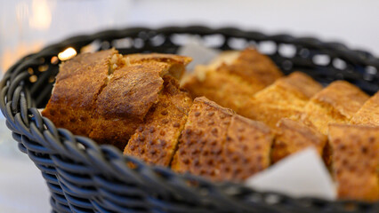 A loaf of white bread cut into slices and arranged in a black basket. 