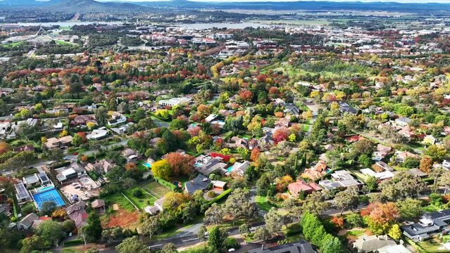 Drone circular motion view of Canberra city buildings and trees on a sunny autumn day