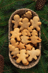 Wicker basket with fresh homemade Christmas gingerbread cookies and fir tree branches. Christmas homemade bakery.
