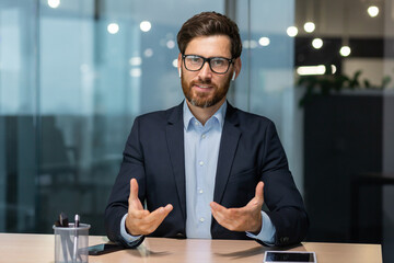 Webcam view, mature businessman office talking with colleagues remotely online, man looking at camera and smiling, successful investor at work in business suit, executive in glasses and beard.