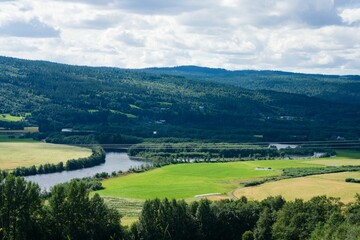 Beautiful landscape scene with green fields, hills, and a river in Selbu, Norway