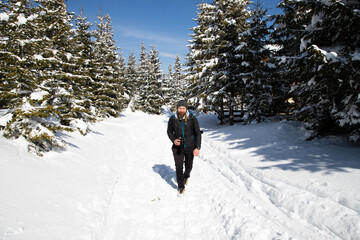 man and dog trekking in big snow in mountains in winter