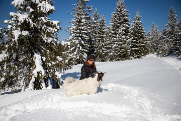 happy woman playing with her dog in big snow