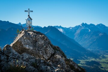 Scenery with a white cross on top of a rock in mountains