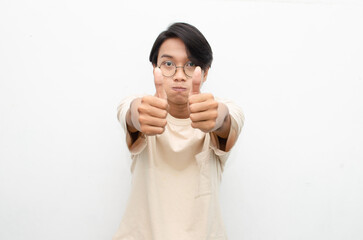 asian young man in casual beige tshirt pointing finger showing something good. man with glasses shocked happily pointing up with copy space isolated over white background. advertisment model concept.