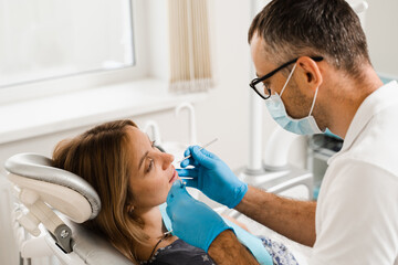 Dentist examines teeth of woman for treatment of toothache. Pain in teeth. Consultation with dentist in dentistry.