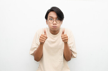 handsome attractive Asian man smiling happily and giving thumbs up as compliment isolated over...