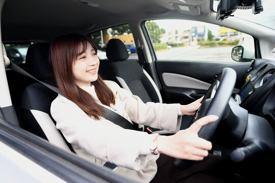 笑顔で運転をする若いアジア人女性
