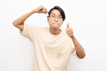 asian young man in casual beige tshirt applying beauty acne serum using pipette and smiling at camera isolated over red background