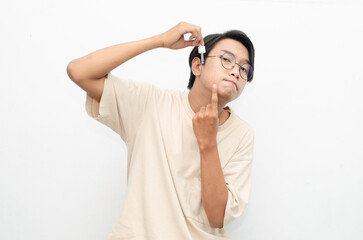 asian young man in casual beige tshirt applying beauty acne serum using pipette and smiling at camera isolated over red background