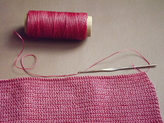 The process of crocheting pink yarn on a purple background