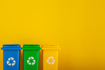 Plastic yellow, green and blue trash can on yellow background