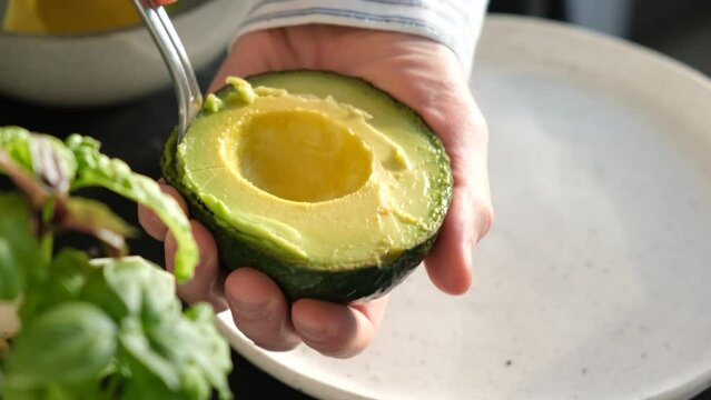 Scoop avocado flesh with spoon. Chef cooking healthy vegan food. Closeup view. Ripe avocado