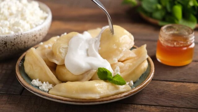 Vareniki, steamed pierogi with sweet cottage cheese, ricotta filling served with sour cream and honey. Ukrainian dessert or sweet breakfast food
