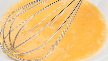 Stirring eggs with whisk in white plate