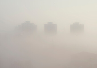 Fog over city with high buildings and urban architecture.  Outline and cityscape. Morning in the town with fog. 