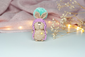 Amigurumi bunny on the background of a warm scarf and a dried flower.