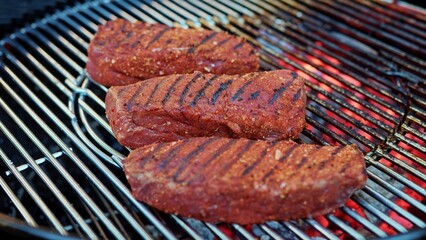 Closeup of three pieces of row steak meats on a grill