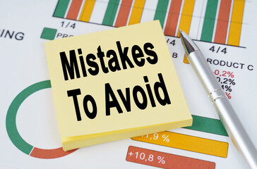 On the business charts are a pen and stickers with the inscription - Mistakes To Avoid
