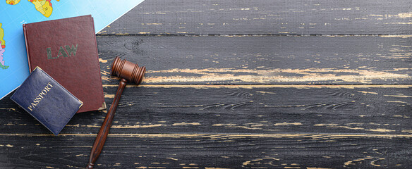 Judge's gavel, book, world map and passport on dark wooden background with space for text....