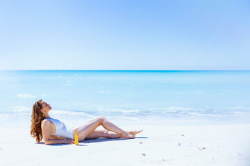Fototapeta na wymiar relaxed modern woman in white swimwear laying at beach