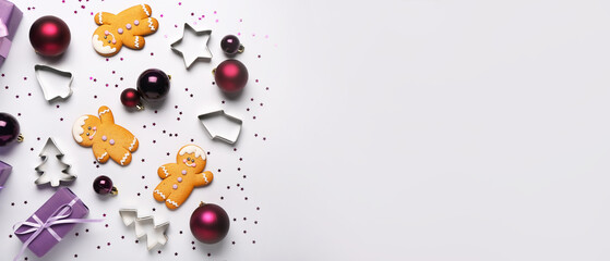 Composition with Christmas gift, balls, cookies and cutters on light background with space for text