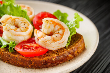 delicious Italian bruschetta with shrimps on a black wooden rustic background