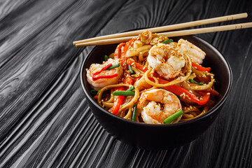 fried wok shrimp noodles on a black wooden rustic background