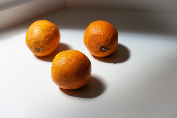 Organic oranges on the table in the kitchen. Season of oranges in Spain. Three ripe oranges in the sunlight.