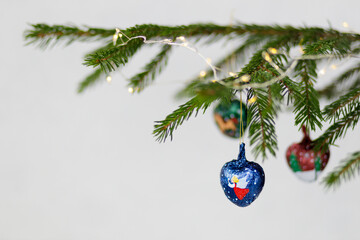  Three blue toys in the shape of a heart close-up on a Christmas tree branch with a garland. Copy space