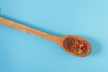 Wooden Spoon with Capsules and Tablets on Blue Background — Healthcare Product Composition with Copy Space