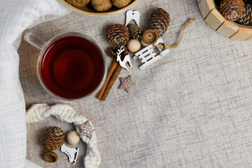 Cup of tea and nuts, cones, cinnamon sticks, small sled and deer, white fabric, macrame wreath. Christmas, winter concept. Flat lay top view.