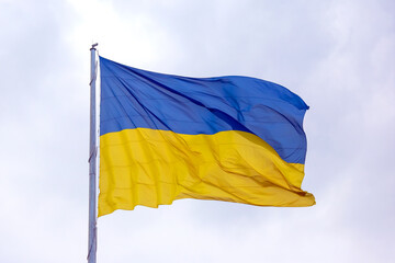 waving in the wind the national flag of Ukraine against the blue sky
