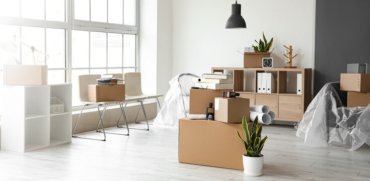 Cardboard boxes with belongings in interior of office on moving day