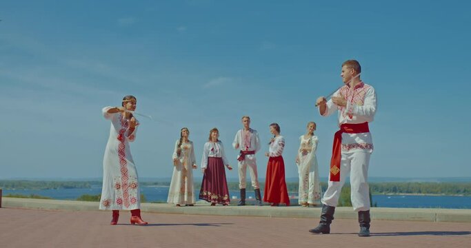 Beautiful Slavic men and women flank with checkers in national vyshyvanka costumes, look at each other with a loving look. 4k, ProRes