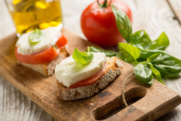 Fototapeta na wymiar Caprese salad traditional italian recipe with mozzarella tomato basil and bread