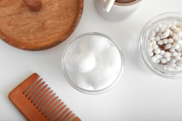 Container with soft cotton wool and swabs on light background