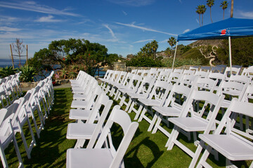 white folding chairs lined up in rows on the park lawn