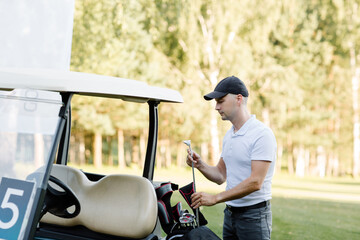 A golfer is going to play golf on the field, he chooses a club. copy space. High quality photo