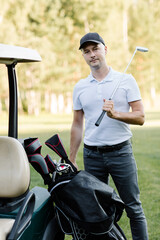 A golfer is going to play golf on the field, he chooses a club. . High quality photo