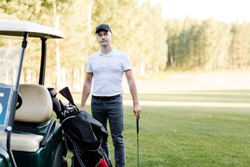 A golfer is going to play golf on the field, he chooses a club. copy space. High quality photo