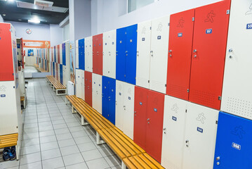 Red lockers in generic locker room with wooden bench