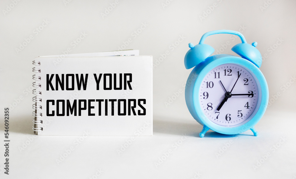 Wall mural notepad with text know your competitors with clock on white background. business concept.