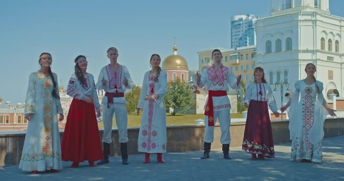 Slavs are dressed in national costumes with embroidery and sing songs on the streets of the city, they are happy. Beautiful women and men rejoice and smile, the Slavs walk in the city, a beautiful